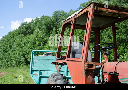 old rustic work tractor in green field outdoor Stock Photo