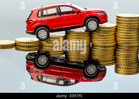 Rising autocosts. A car takes up a coin pile, Steigende Autokosten. Ein Auto fuehrt einen Muenzstapel hinauf Stock Photo