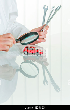 A model of a car is examined by a doctor. Symbolic photo for workshop, service and autopurchase., Ein Modell eines Autos wird vo Stock Photo