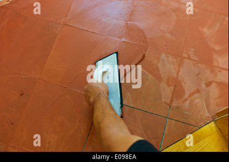 A tiler applies the joint mass on flagstones. Verfugen of tiles., Ein Fliesenleger traegt auf Bodenfliesen die Fugenmasse auf. V Stock Photo