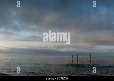 Warning marker posts in sea, cloudy sky,Shoreham, Sussex Stock Photo