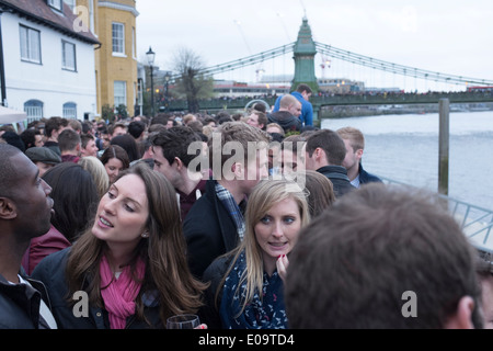 Spectators on the bank of the River Thames at Hammersmith during the annual Oxford and Cambridge Boat Race. Stock Photo