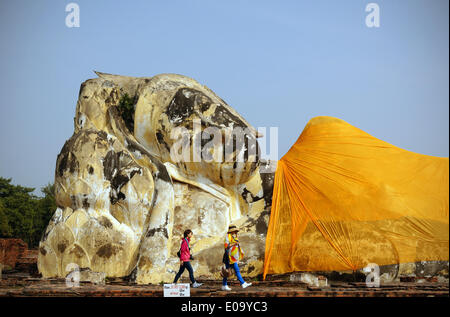 Ayutthaya, Thailand. 30th Dec, 2014. Tourists walk past the so-called 'reclining' or 'sleeping' Buddha at the Wat Lokayasutharam temple (earth temple) in Ayutthaya, Thailand, 30 December 2014. The statue measures around 40 metres in length, consists of overlaying bricks and is located at the south-western end of the old palace. The former capital of the kingdom of Siam, located around 70 kilometre of Bangkok, was one of the major metropolis in Southeast Asia in the 18th century. Photo: Soeren Stache/dpa - NO WIRE SERVICE -/dpa/Alamy Live News Stock Photo