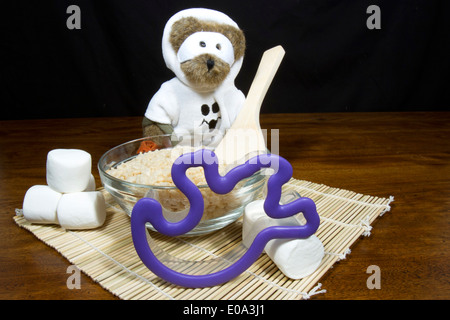 Cute halloween bear dressed as a ghost making ghost shaped puffed rice cereal cookie treats Stock Photo