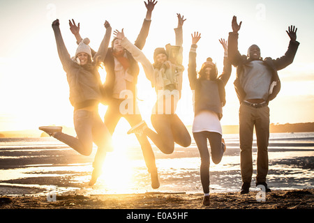 Five adult friends jumping mid air on the beach Stock Photo