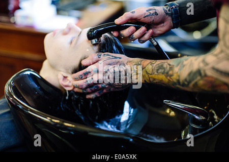 Close up of barber washing young mans hair Stock Photo