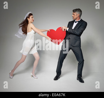 Bride and bridegroom fighting over heart Stock Photo