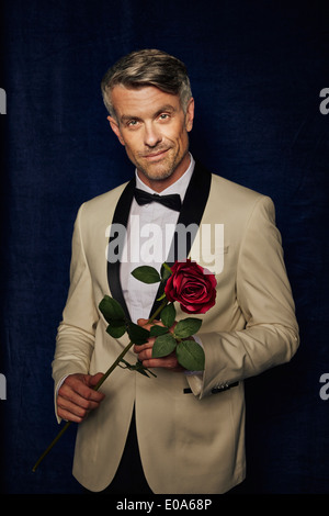 Man in tuxedo holding single rose Stock Photo