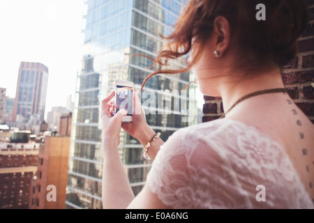 Young woman using smartphone to photograph Manhattan, New York City Stock Photo