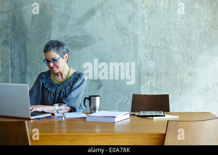 Mature businesswoman at conference table working on laptop Stock Photo