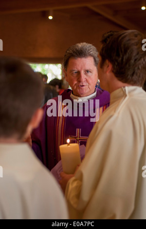 A robed Catholic priest talks with his altar boys before celebrating mass in Laguna Niguel, CA. Stock Photo