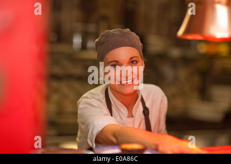 Portrait of young female chef serving over cafe counter Stock Photo
