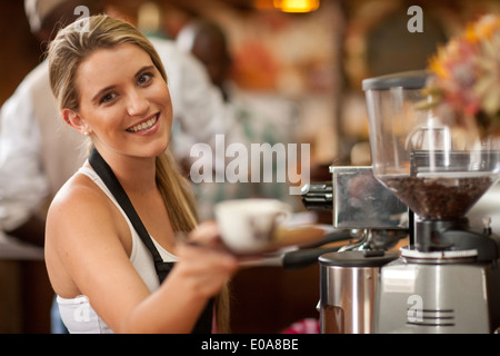 Portrait of young woman preparing cup of coffee in cafe Stock Photo