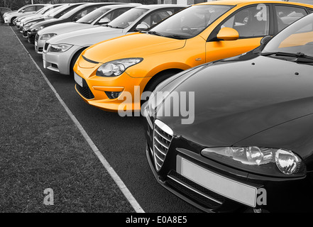 Row of used cars for sale in row with one in colour, great concept for choice of perfect vehicle to buy. Stock Photo