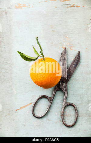 Ripe orange with leaf and vintage scissors on textured background Stock Photo