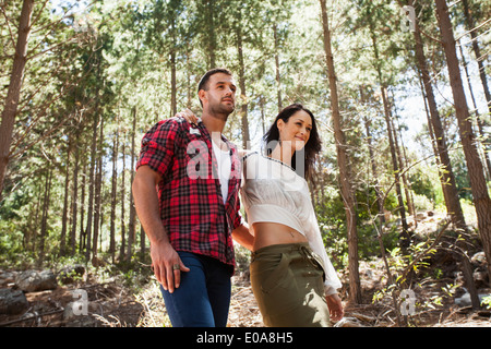 Young couple walking through forest, arm around Stock Photo