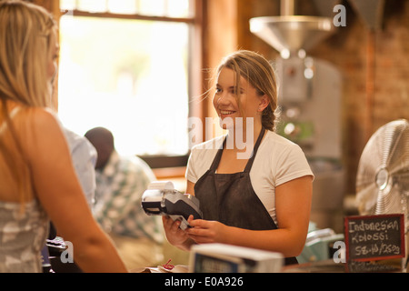 Young woman serving customer in coffee shop Stock Photo