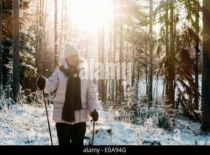 Mid adult woman nordic walking in snow covered forest Stock Photo