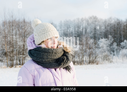 Mid adult woman wearing winter clothing in snow covered field Stock Photo