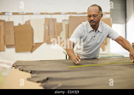 Upholsterer measuring leather on workbench Stock Photo