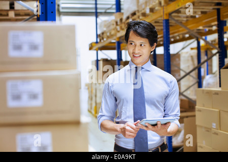 Mid adult male manager using digital tablet in distribution warehouse Stock Photo