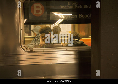 Tired young man rides the B train in New York City. Stock Photo