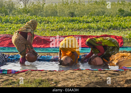 Women filling clay pots with water, Nagla Kachhpura, Agra, India Stock Photo