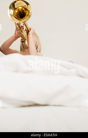 Girl playing trumpet in bed Stock Photo