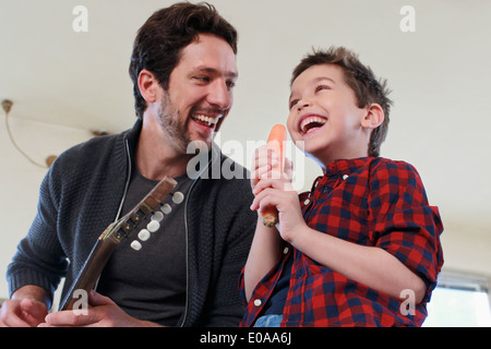 Father and son with guitar and carrot microphone Stock Photo