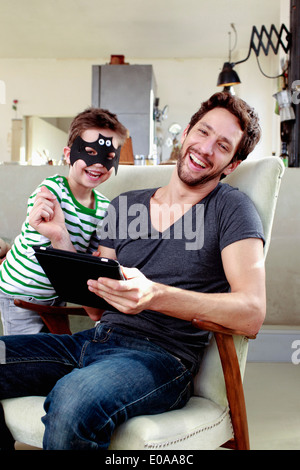 Father and son sitting on chairs with digital tablet Stock Photo