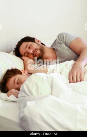 Father and young son sleeping in bed Stock Photo