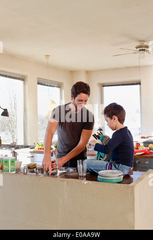 Father and young son clearing up in kitchen Stock Photo