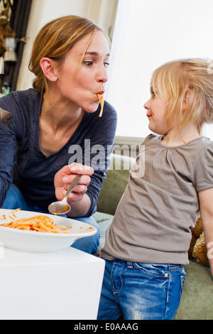 Mid adult mother eating spaghetti with her daughter