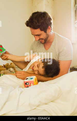 Father and young son playing on bed Stock Photo