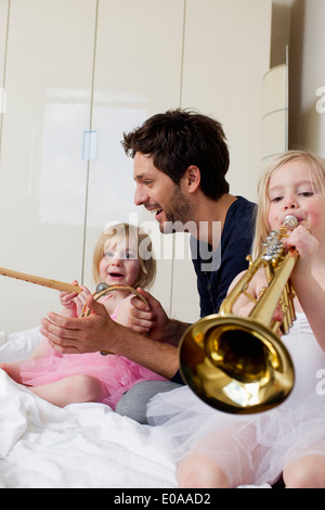 Father and two young daughters playing music Stock Photo