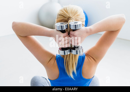 Young woman lifting weights, rear view Stock Photo