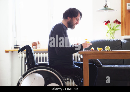 Man in wheelchair cutting fruit Stock Photo