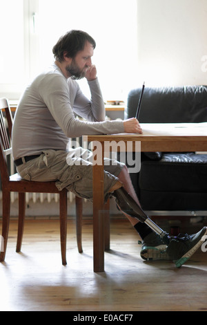 Disabled man using laptop in living room Stock Photo