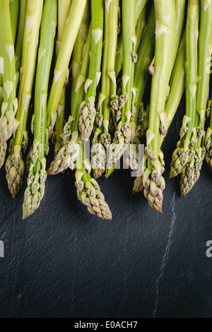 Young green asparagus on black glass. Top view. Stock Photo