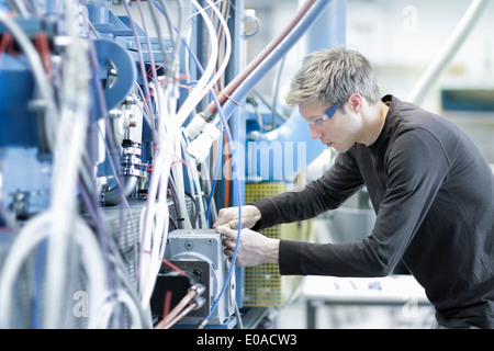 Mid adult male technician maintaining cables in engineering plant Stock Photo