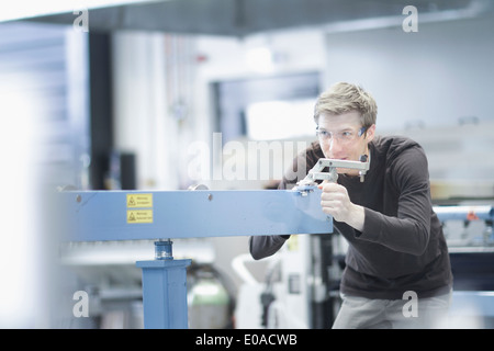 Mid adult male technician with measuring equipment in engineering plant Stock Photo