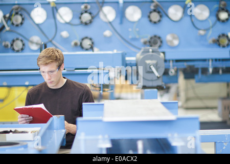 Mid adult male technician checking paperwork in engineering plant Stock Photo
