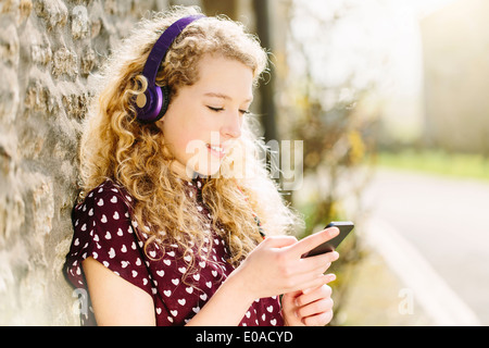 Portrait of teenage girl in village with headphones and smartphone