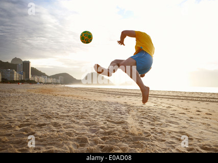 Mid adult man playing soccer on Copacabana beach, Rio De Janeiro, Brazil Stock Photo