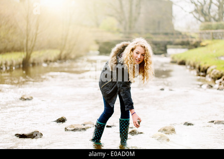 Teenage girl picking up stones in rural river Stock Photo