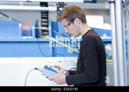 Mid adult male technician monitoring machines in engineering plant Stock Photo