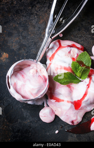 Melting strawberry ice cream with fresh mint and metal spoon over black table. Top view Stock Photo