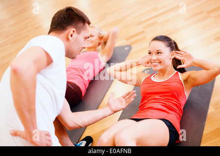 group of smiling women doing sit ups in the gym Stock Photo