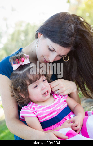 Mixed Race Loving Mother Consoles Her Crying Baby Daughter in Park. Stock Photo