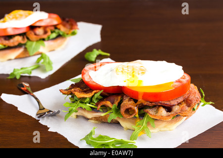 Open-faced BLT sandwich with provolone cheese, arugula, bacon, tomato and a fried egg on sweet potato bread Stock Photo